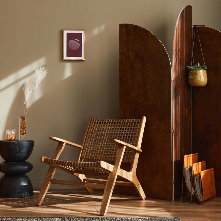 Fancy interior of living room with design sofa,  rattan armchair, wooden room screen, pillows, picture frame, carpet decor and elegant personal accessories in stylish home decor. Template.